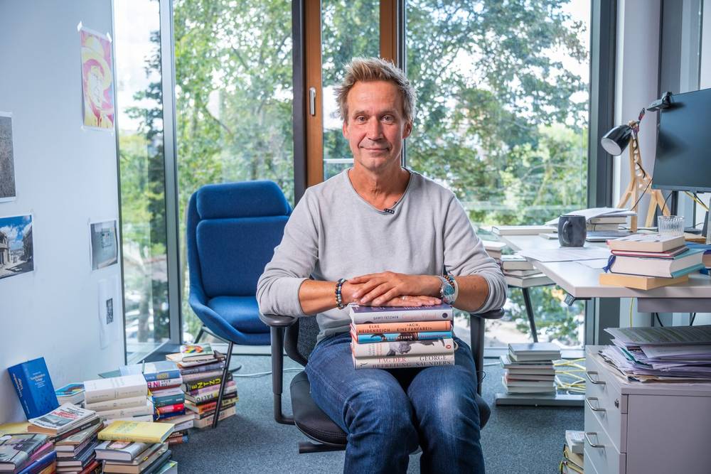 Porträt im Büro zwischen Bücherstapeln